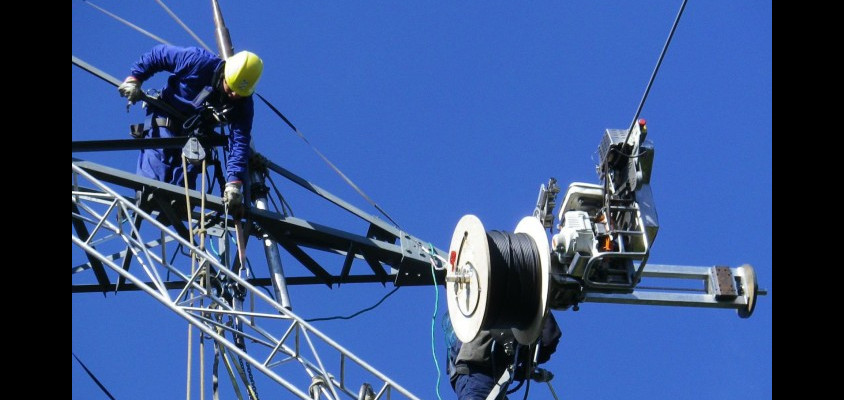 operari instaŀlant cable de fibra òptica en una torre elèctrica